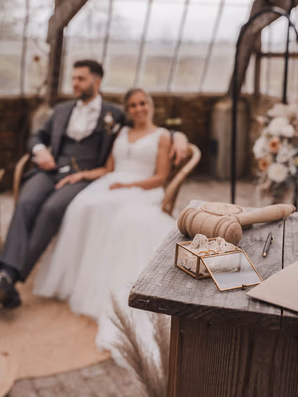 katheder met hamer trouwambtenaar lisanne op voorgronden bruidspaar faded op de achtergrond