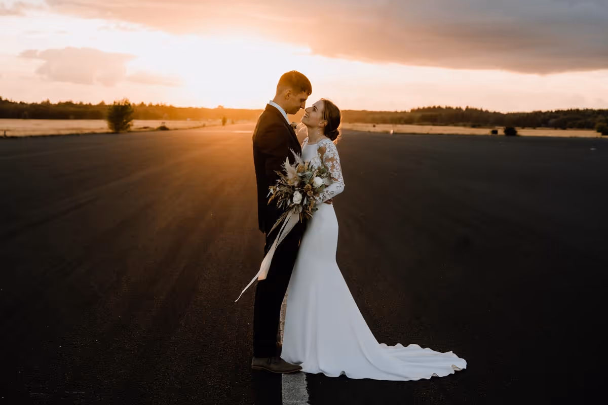 Brruidspaar met lange weg op de achtergrond en ondergaande zon