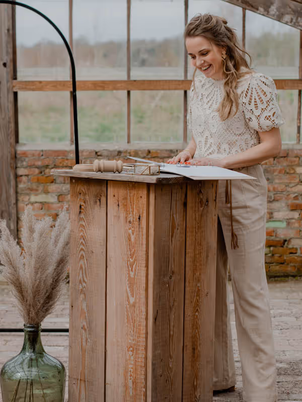 Trouwambtenaar Lisanne lachend achterkatheder, ze leest de speech voor het bruidspaar voor